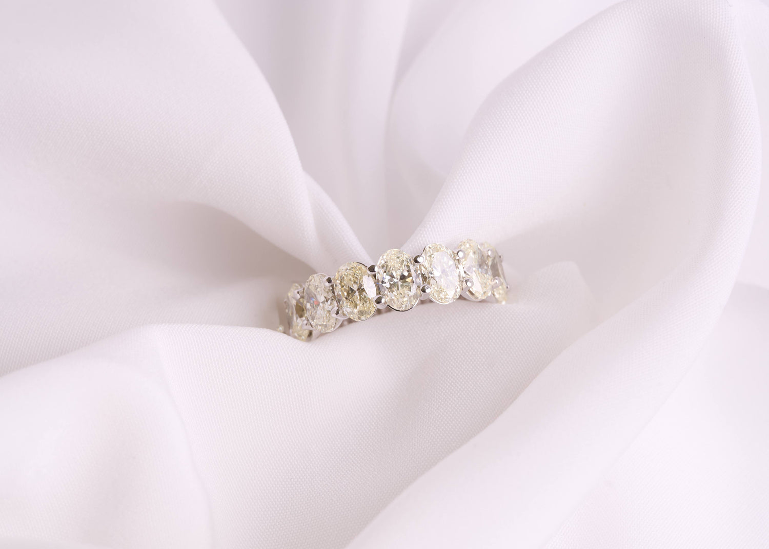 Silver ring with oval diamond stones on a white fabric background