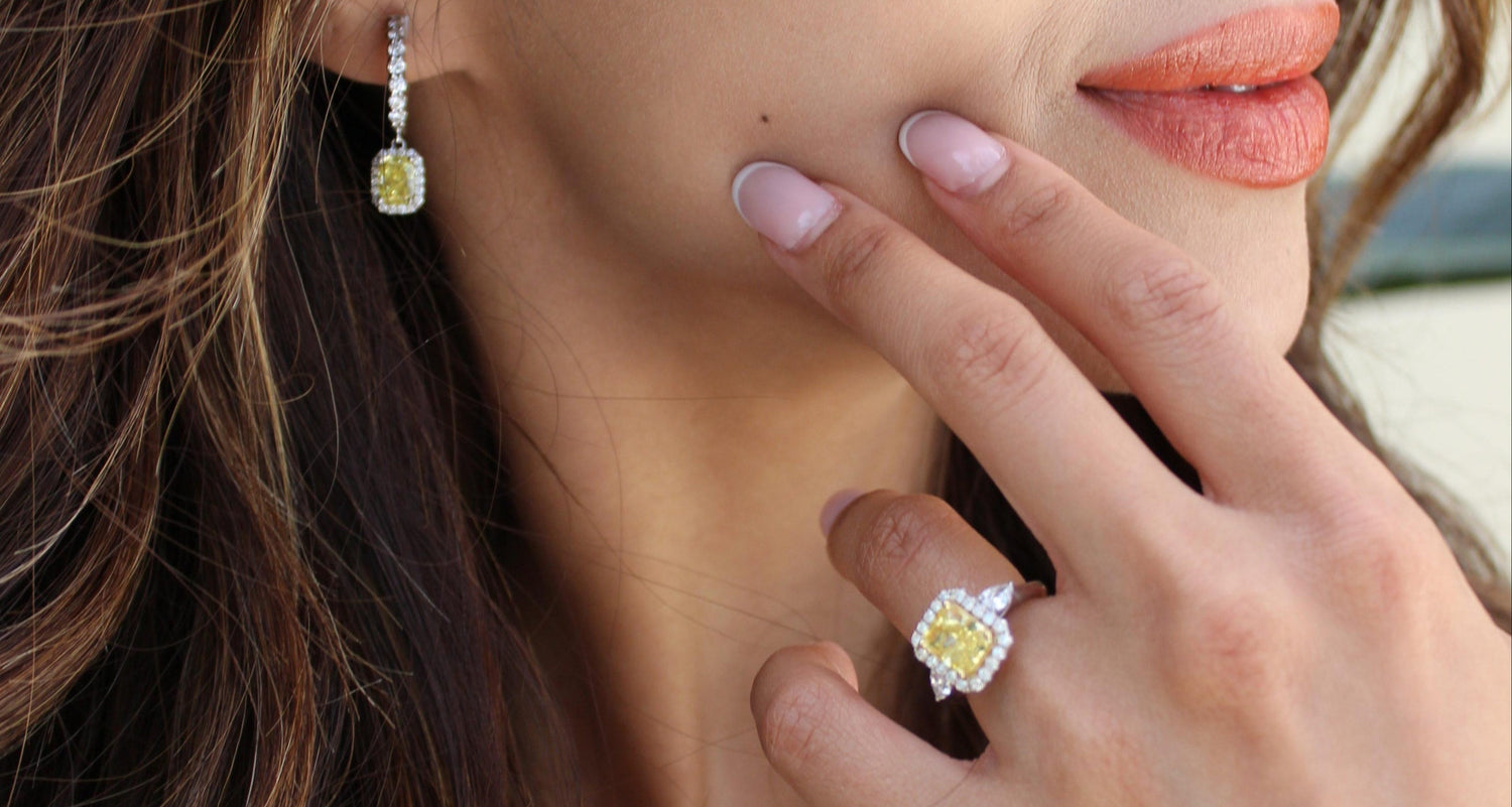 Close-up of a woman wearing diamond earrings and a diamond ring with a blurred outdoor background